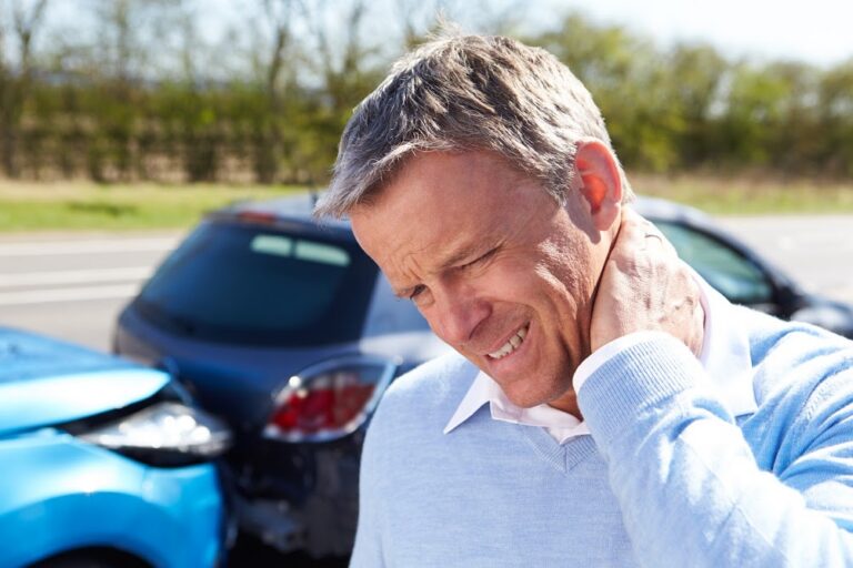 Man experiencing neck pain with car accident in background