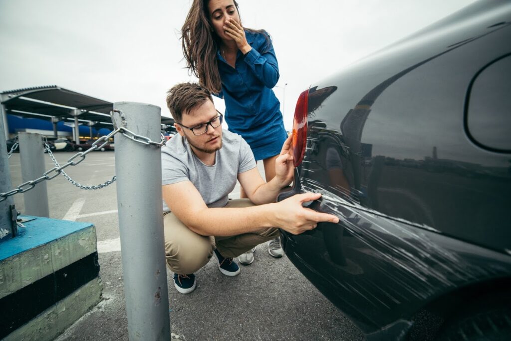 Man and Woman examining scratches on vehicle
