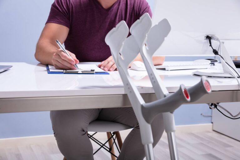close up of crutches and man filling out form on table