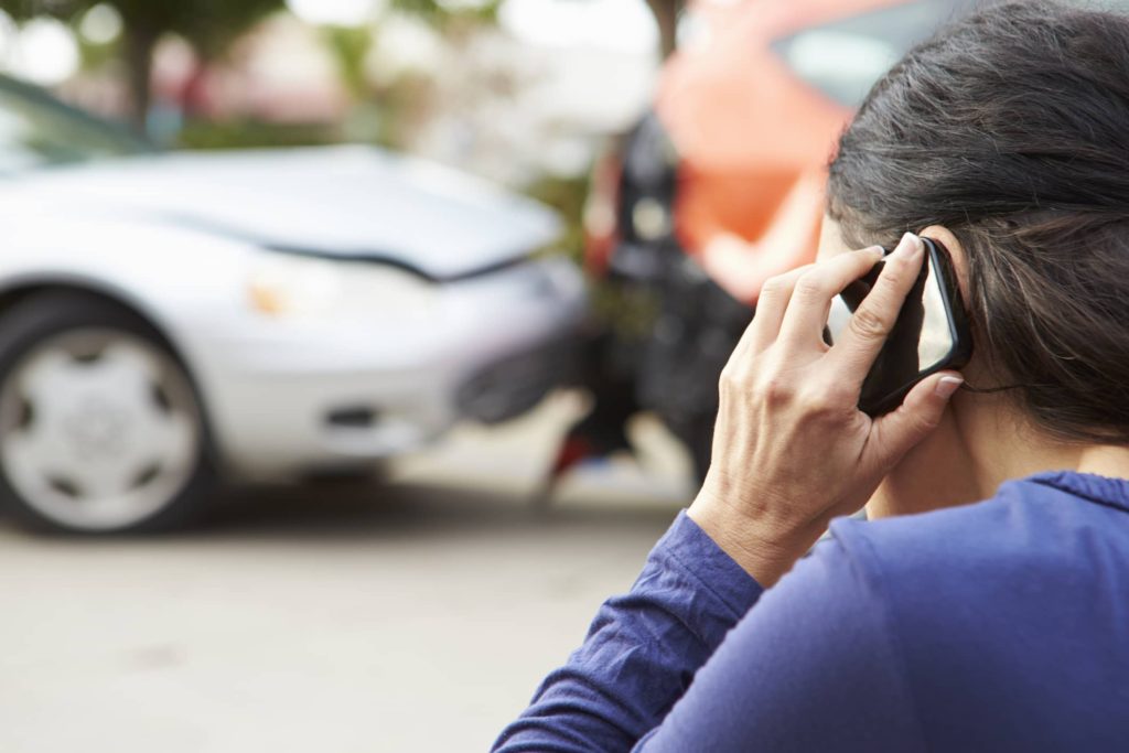 women on phone looking out at car accident