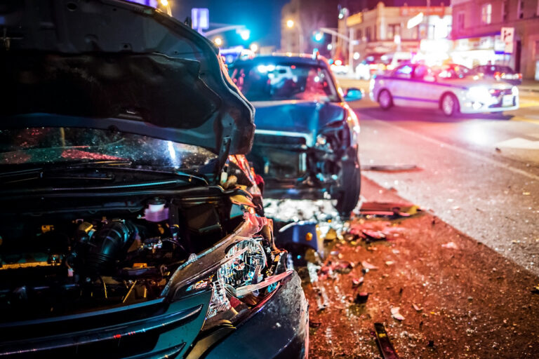 Car Crash at night with police car in background