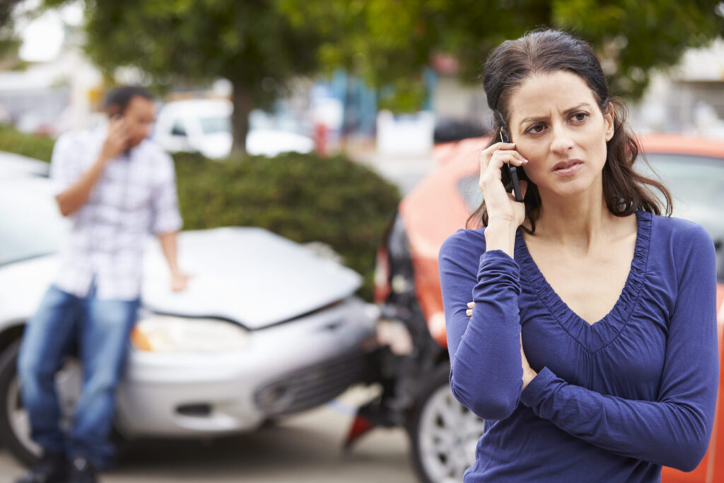 Woman using cellphone after car accident