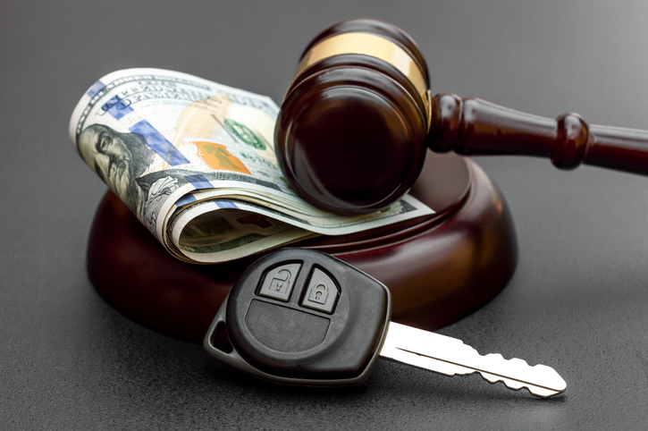 Judge's gavel with car key and money on black.