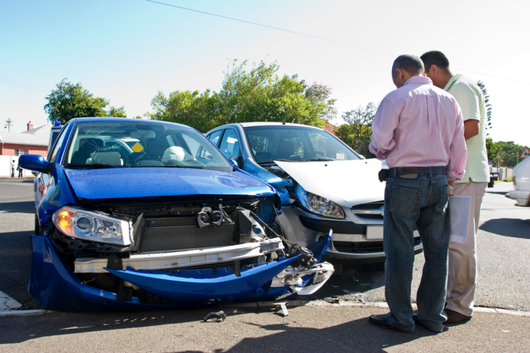 Two men conferring next to two smashed cars.