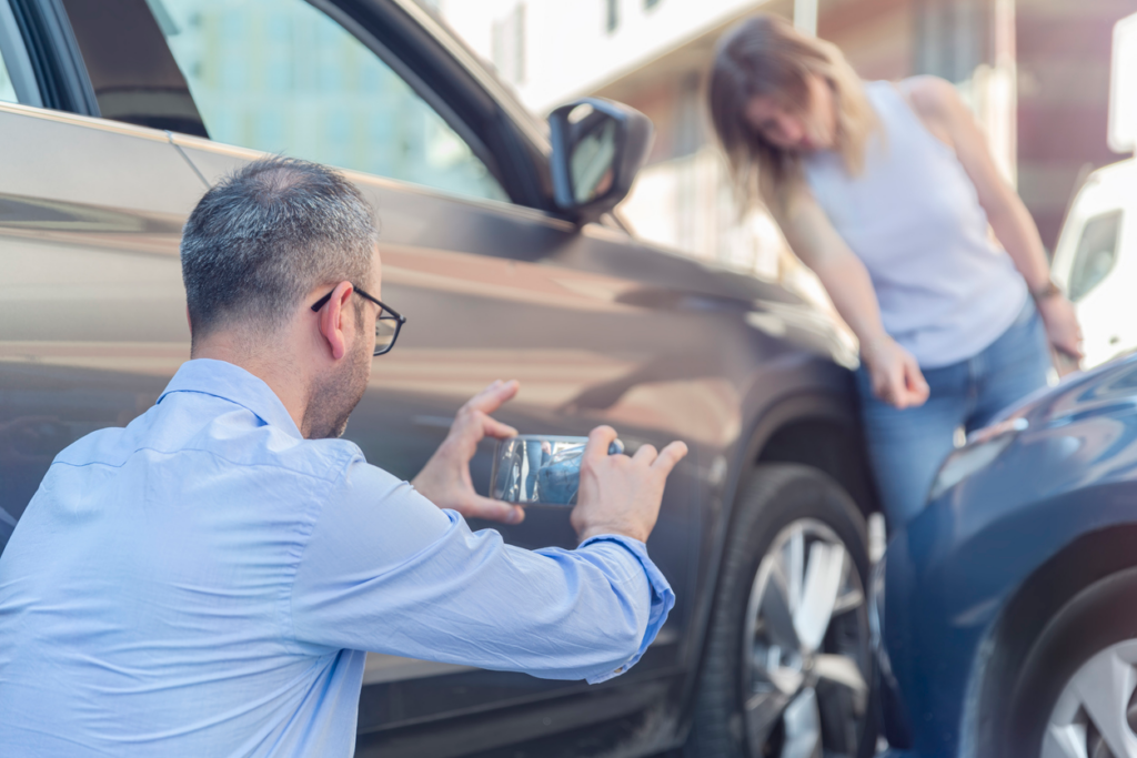 Man documenting vehicle damage after car accident